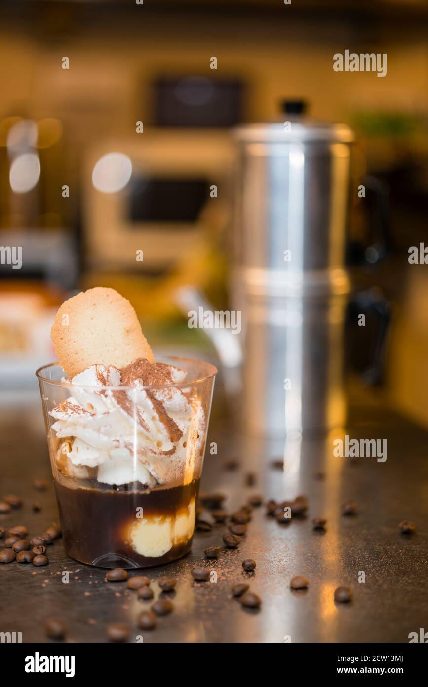 Préparation artisanale d'une tasse de glace italienne glace glace galato affogato noyée dans un café expresso avec de la crème fouettée et des biscuits à la langue du chat. Banque D'Images