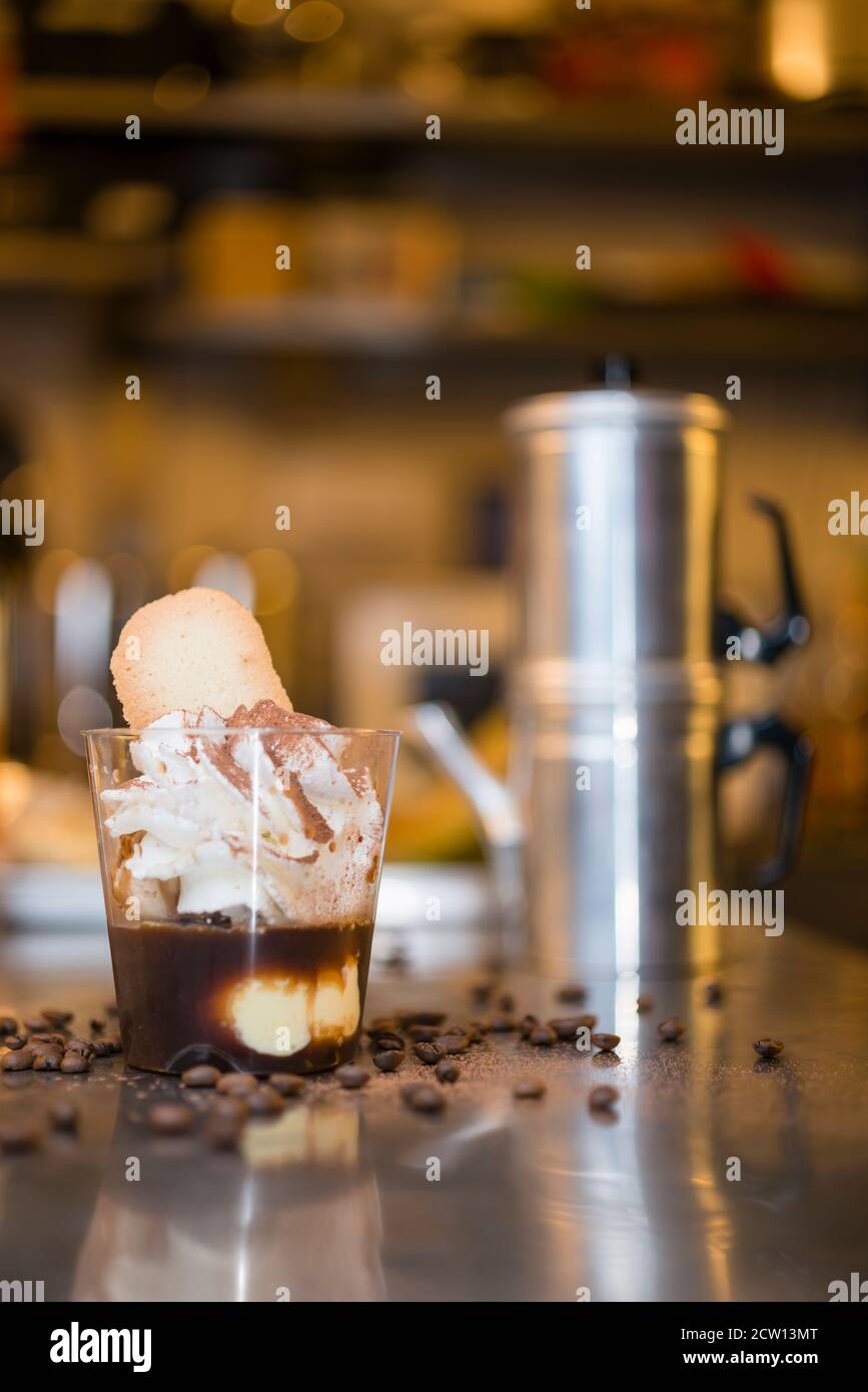 Préparation artisanale d'une tasse de glace italienne glace glace galato affogato noyée dans un café expresso avec de la crème fouettée et des biscuits à la langue du chat. Banque D'Images