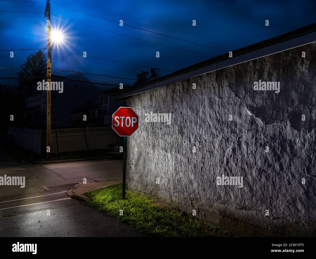 Panneau stop avec lumière de rue illuminant le mur de stuc texturé, West Conshohocken, Pennsylvanie, Etats-Unis Banque D'Images