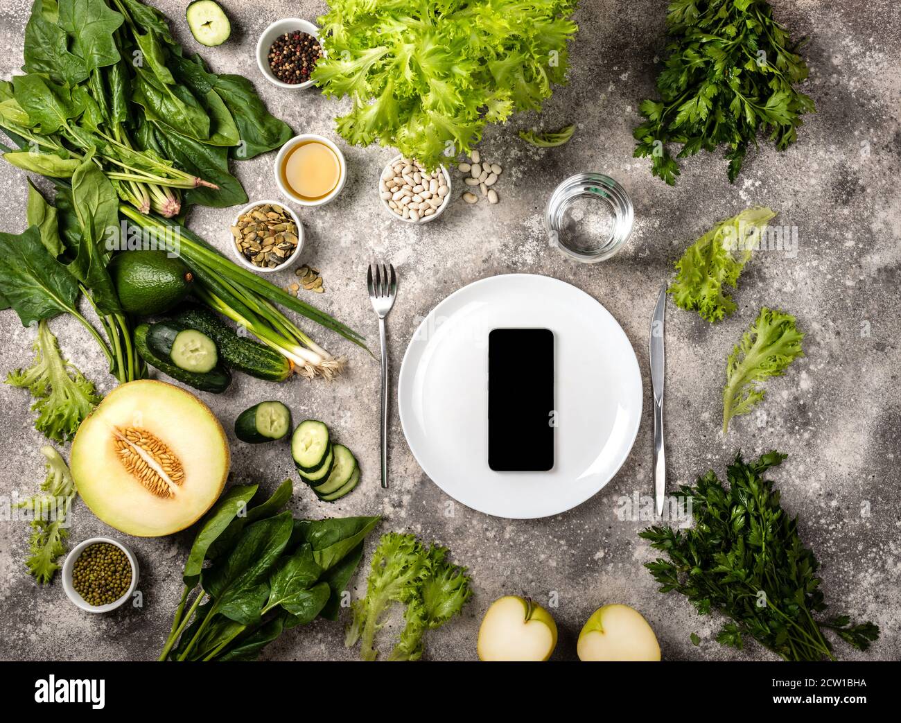 Smartphone sur plaque vide différents légumes et herbes. Banque D'Images