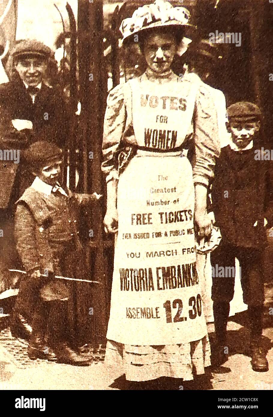 1908 SUFFRAGETTES - 1908 UNE femme de ménage habille comme un Panneau publicitaire humain annonçant une réunion publique pour les suffragettes anglais exigeant votes pour les femmes Banque D'Images