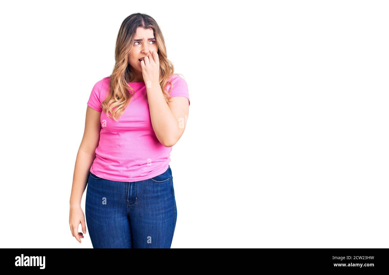 Jeune femme caucasienne portant des vêtements de sport semble stressée et nerveuse avec les mains sur la bouche piquant les ongles. Problème d'anxiété. Banque D'Images