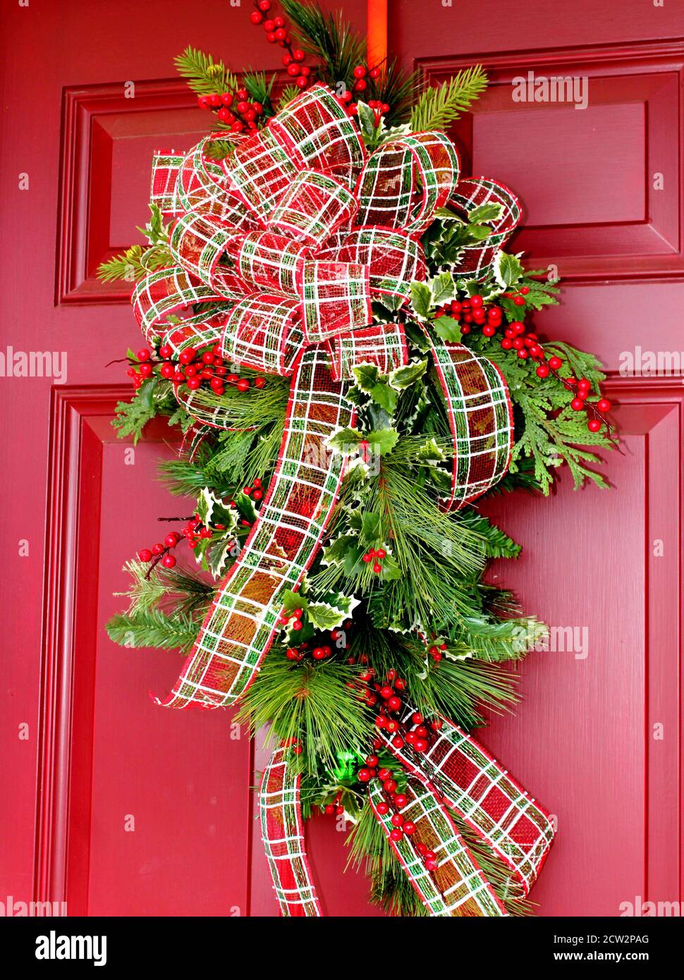 Couronne de Noël ornée d'un noeud sur une porte en bois rouge Photo Stock -  Alamy