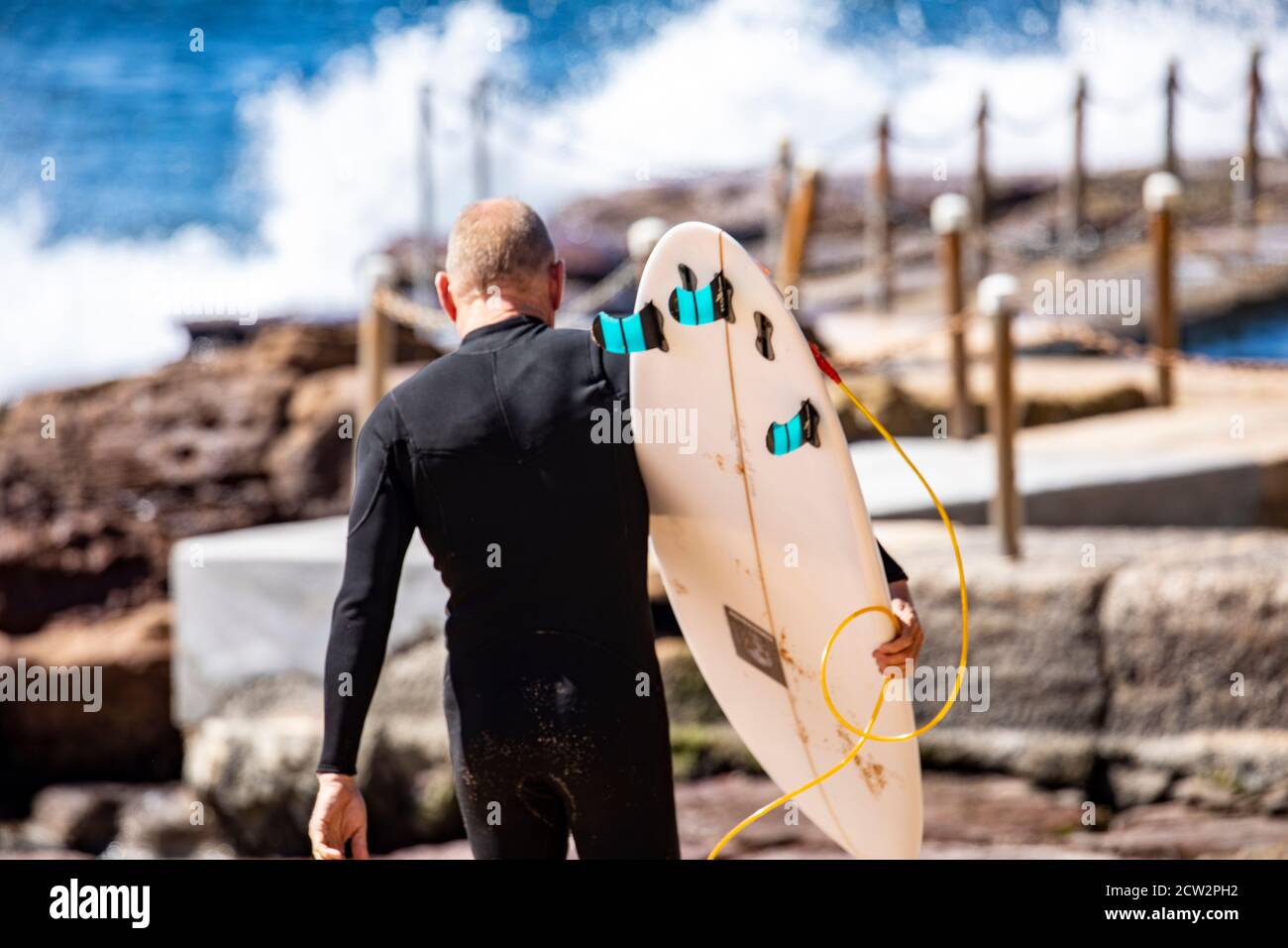 Homme australien d'âge moyen portant une combinaison de randonnée jusqu'au surf Portant sa planche de surf,Sydney,NSW,Australie Banque D'Images