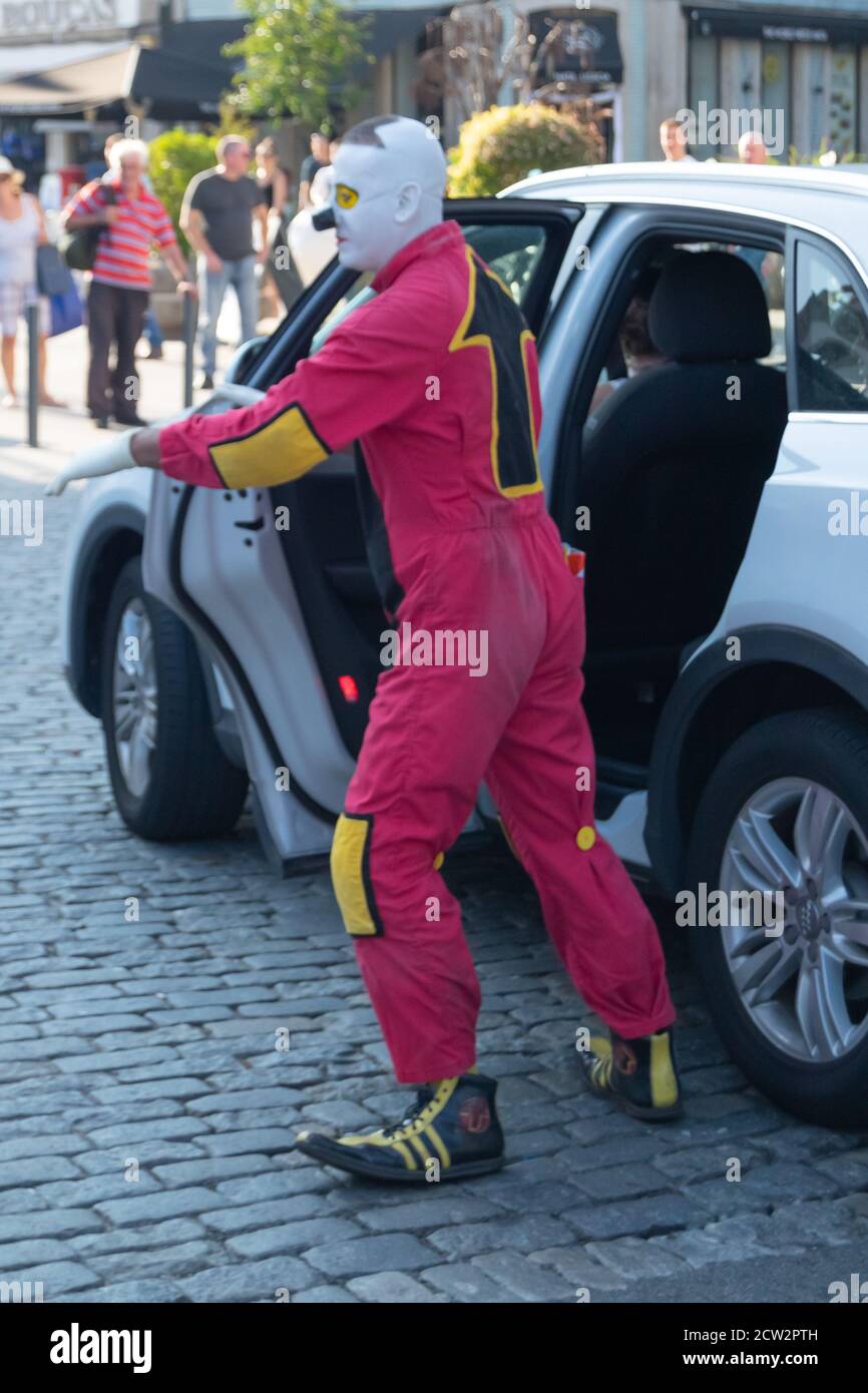 Clown en rouge avec flèche à l'arrière sortant Voiture blanche dans la rue à Braga ville au Portugal Banque D'Images