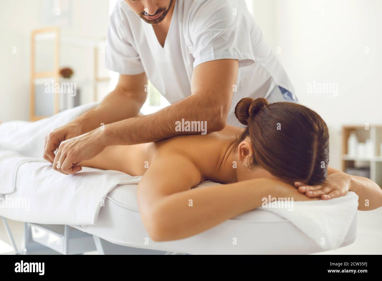 Masseuse professionnelle effectuant un massage corporel pour une jeune femme allongée table de massage Banque D'Images