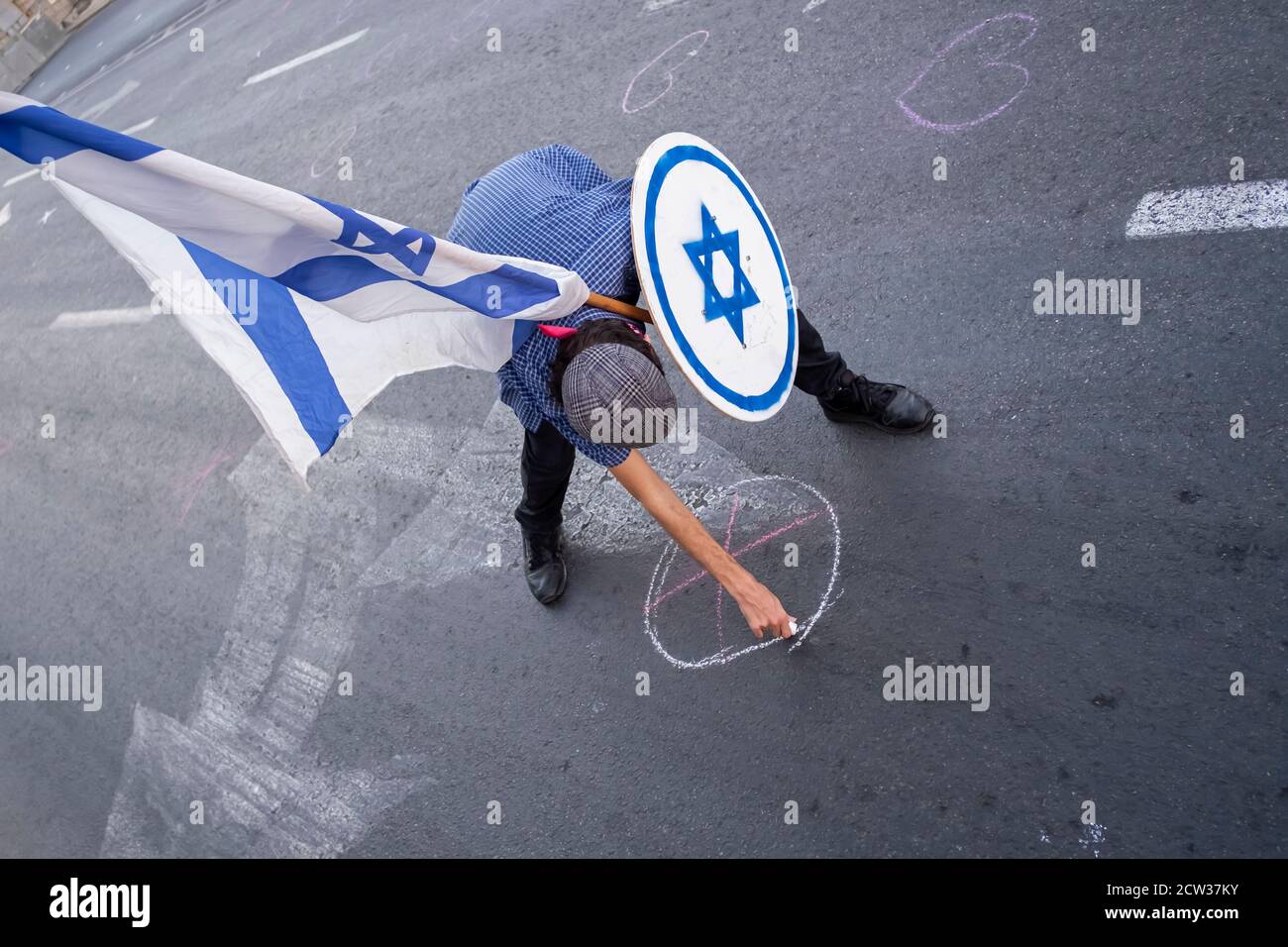 JÉRUSALEM, ISRAËL - SEPTEMBRE 26 : Un manifestant tient un bouclier contre l'étoile juive de David alors qu'il marque la prise de distance sociale selon la nouvelle réglementation Covid-19 peu avant qu'une manifestation de masse ait eu lieu près de la résidence officielle du premier ministre dans un cadre national visant à enrayer la pandémie du coronavirus le 26 septembre. 2020 à Jérusalem, Israël. Une vague de protestations a balayé Israël au cours des derniers mois pour exiger la démission de Netanyahou suite à son inculpation pour corruption et à la gestion de la pandémie du coronavirus Banque D'Images