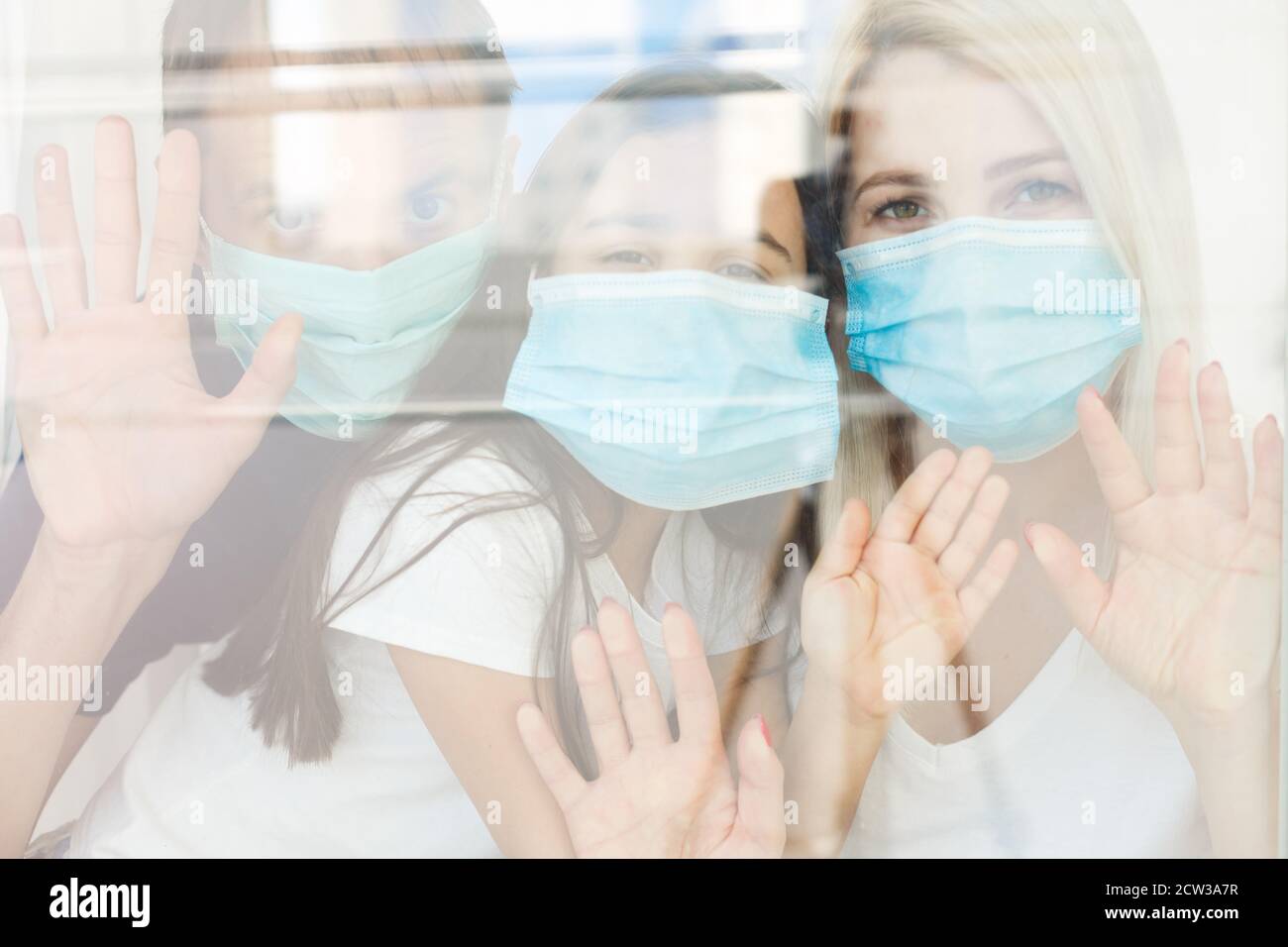 Famille, debout derrière la fenêtre, à la maison, quarantaine due au coronavirus Banque D'Images