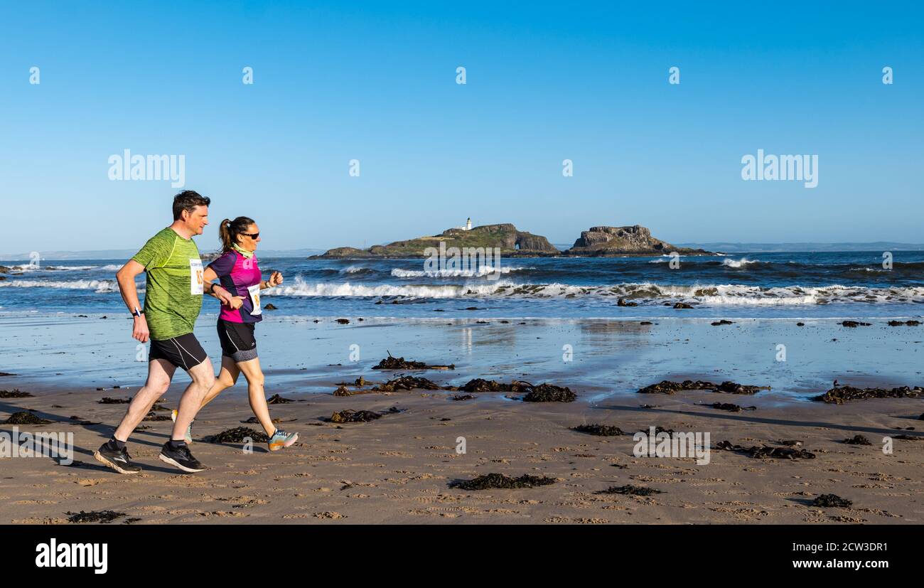 East Lothian, Écosse, Royaume-Uni, 27 septembre 2020. Scurry Running Event : les coureurs participent à un événement de course amusant de la plage de Yellowcraig à North Berwick et de retour sur une belle matinée ensoleillée d'automne. Fidra Island est à l'arrière-plan comme un couple courir sur la plage Banque D'Images