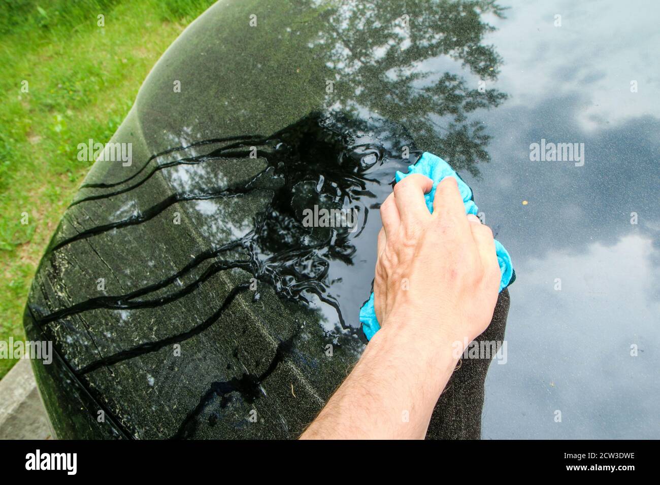Le détail printanier d'une voiture sale du pollen. La main la nettoie avec un chiffon humide. Banque D'Images
