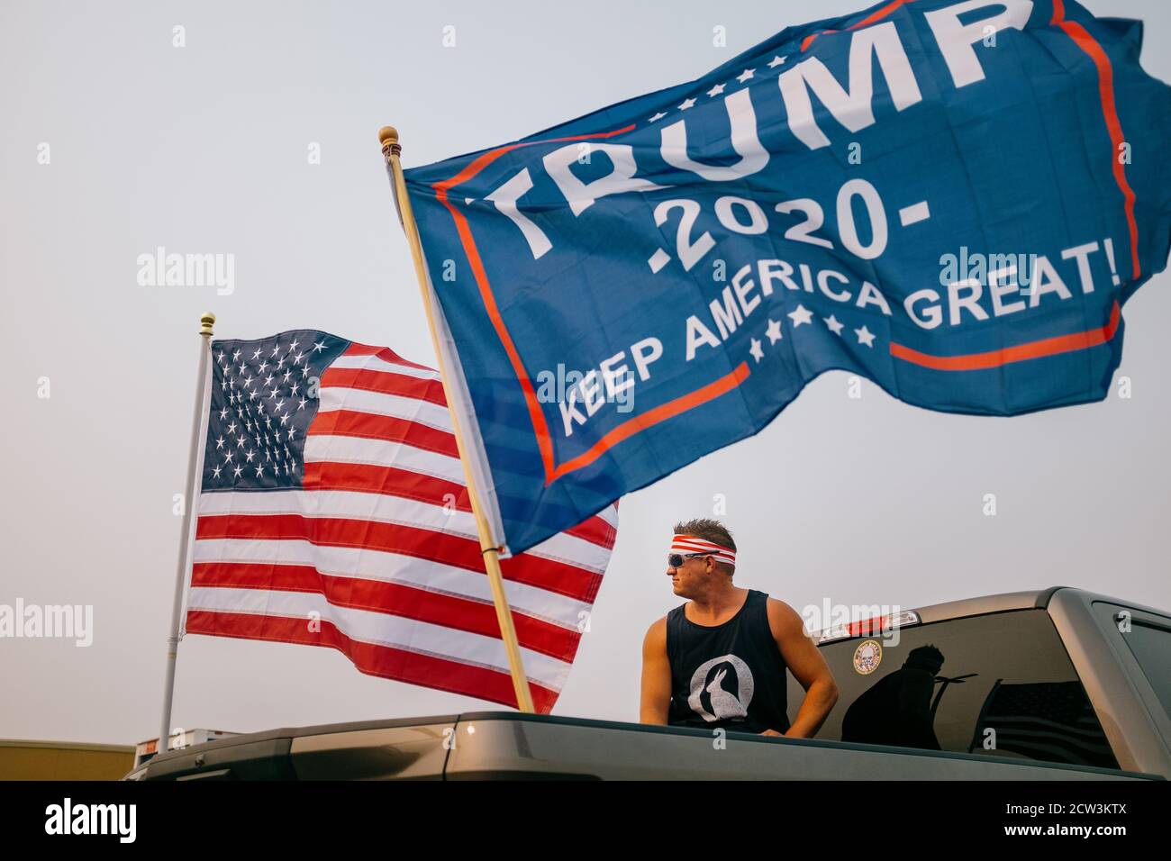 Un supporter de Trump 2020 se tient à l'arrière de son camion de pick-up battant LES drapeaux DE TRUMP 2020 et Q-Anon. Banque D'Images