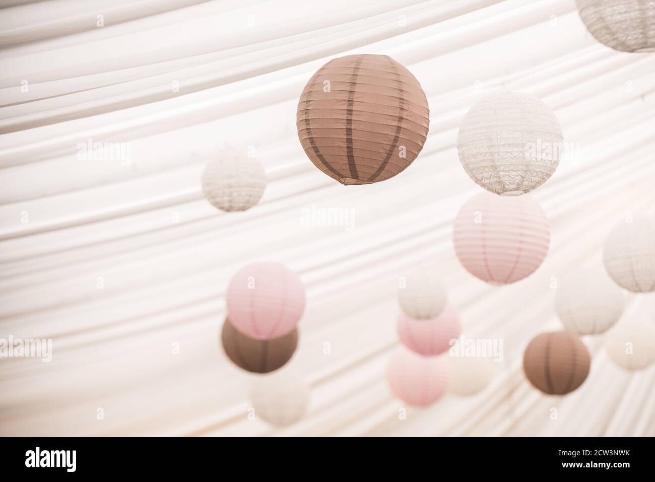 Lanternes en papier pastel suspendues au plafond blanc Banque D'Images