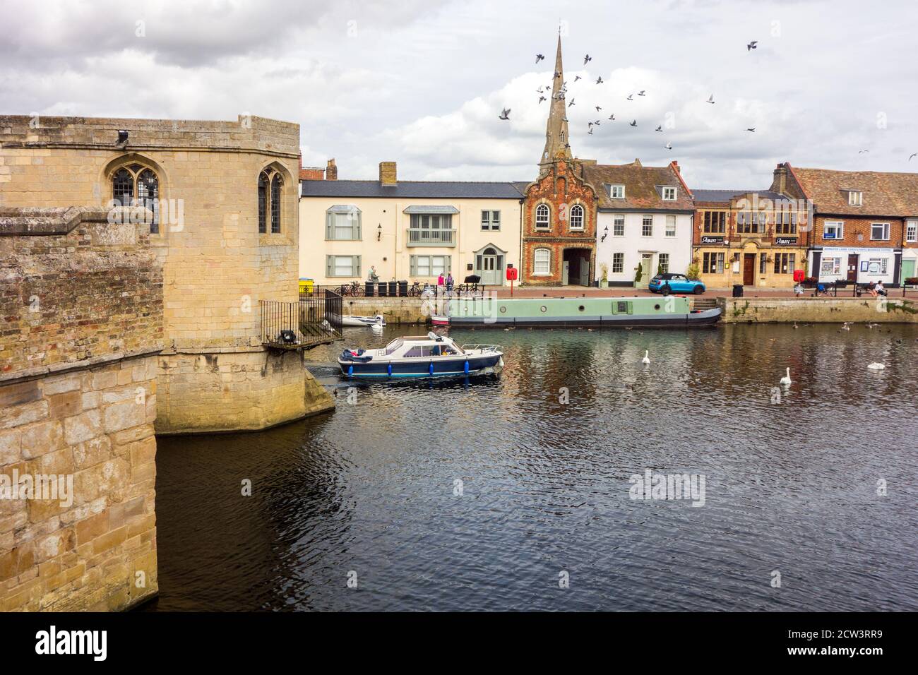 Bateau à rames et embarcation de plaisance sur le grand fleuve Ouse à St Ives Cambridgeshire Angleterre, vu du pont médiéval en pierre et de la chapelle Banque D'Images