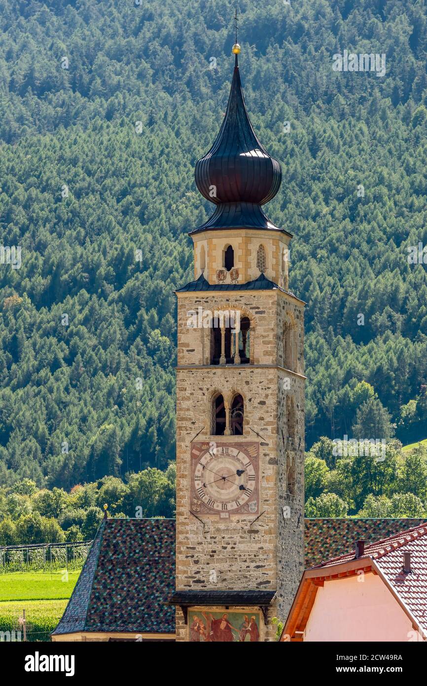 Le clocher et le toit carrelé de l'église de San Pancrazio à Glorenza, Tyrol du Sud, Italie, contre la montagne couverte d'arbres Banque D'Images