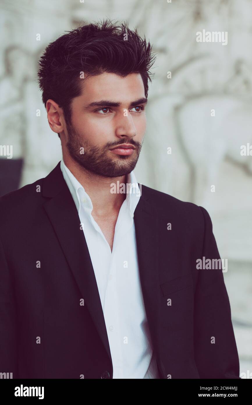Beau et jeune homme avec des cheveux et une barbe stylées. Portrait de l'homme charmant. Chemise et veste blanches. Banque D'Images