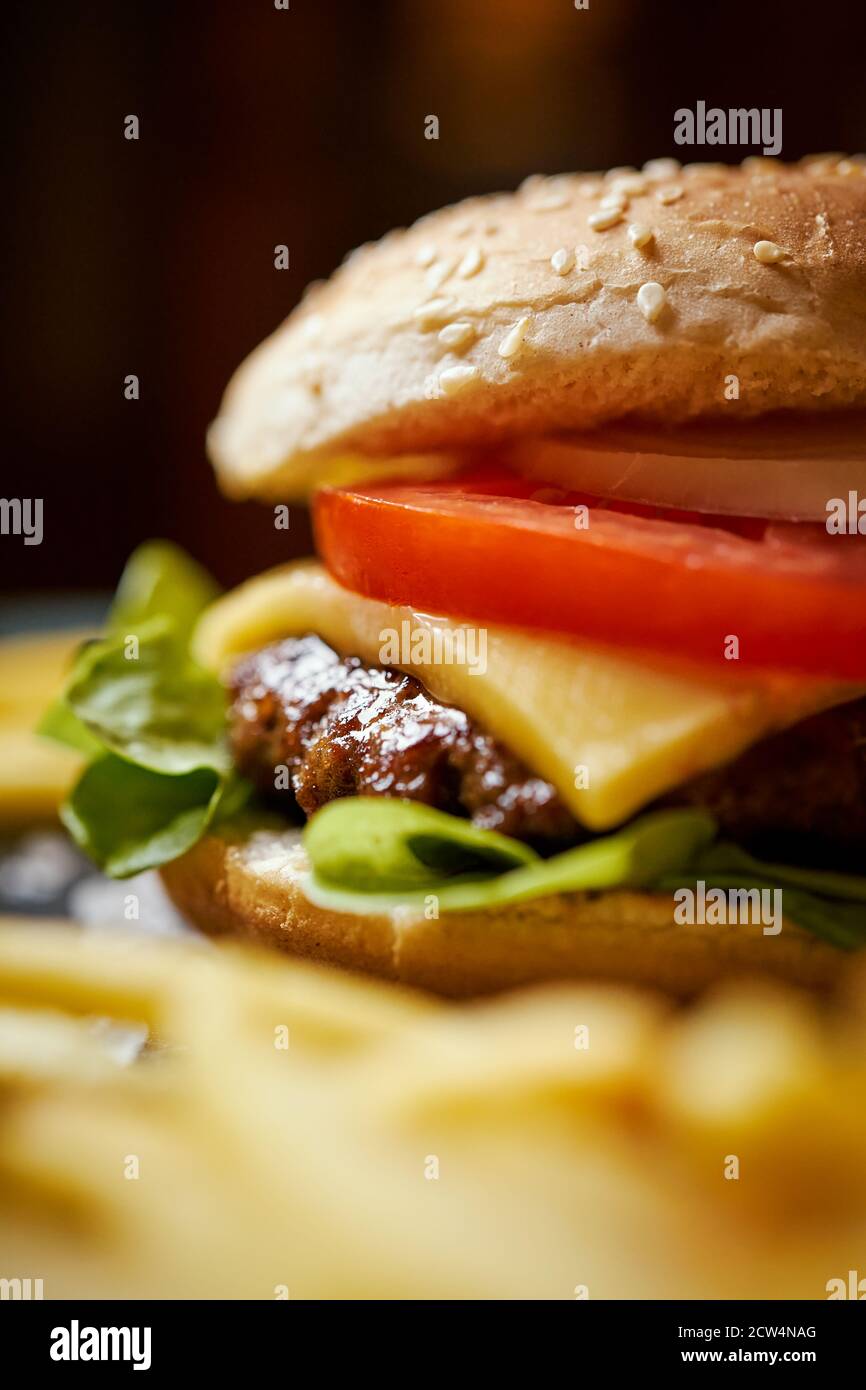 cheeseburger entouré de frites sur une table noire Banque D'Images