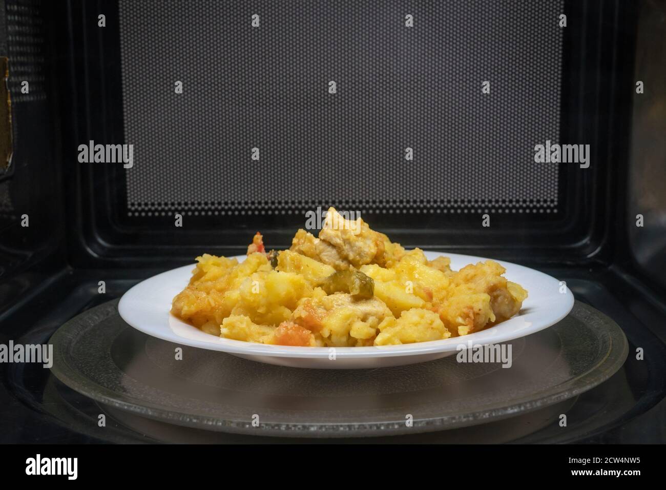 Cuisson, chauffage des aliments au micro-ondes. Pommes de terre cuites à la  viande, légumes sur une assiette blanche dans le micro-ondes vue de dessus  Photo Stock - Alamy
