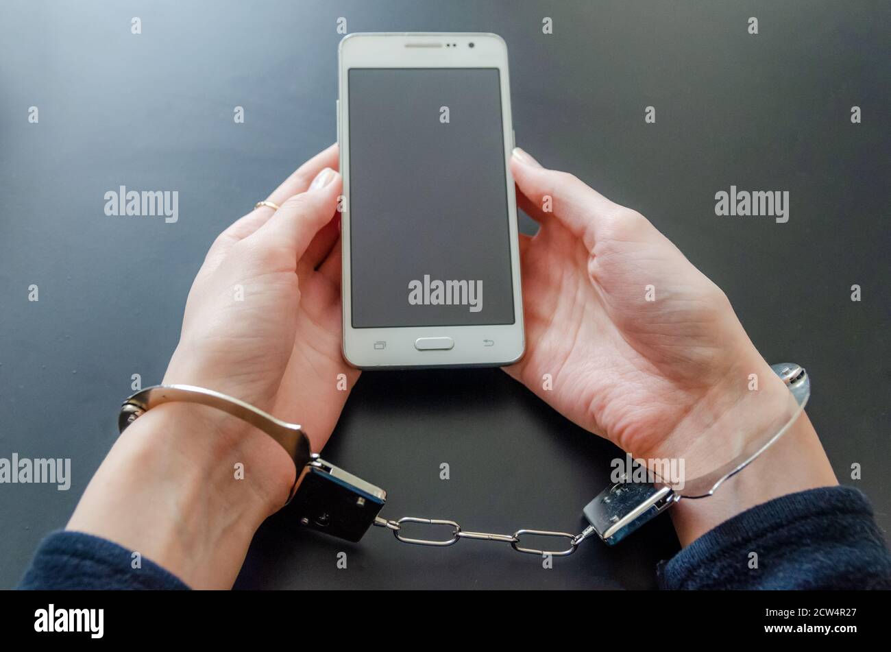 Arrêté femme dans les menottes tout en tenant le smartphone Banque D'Images