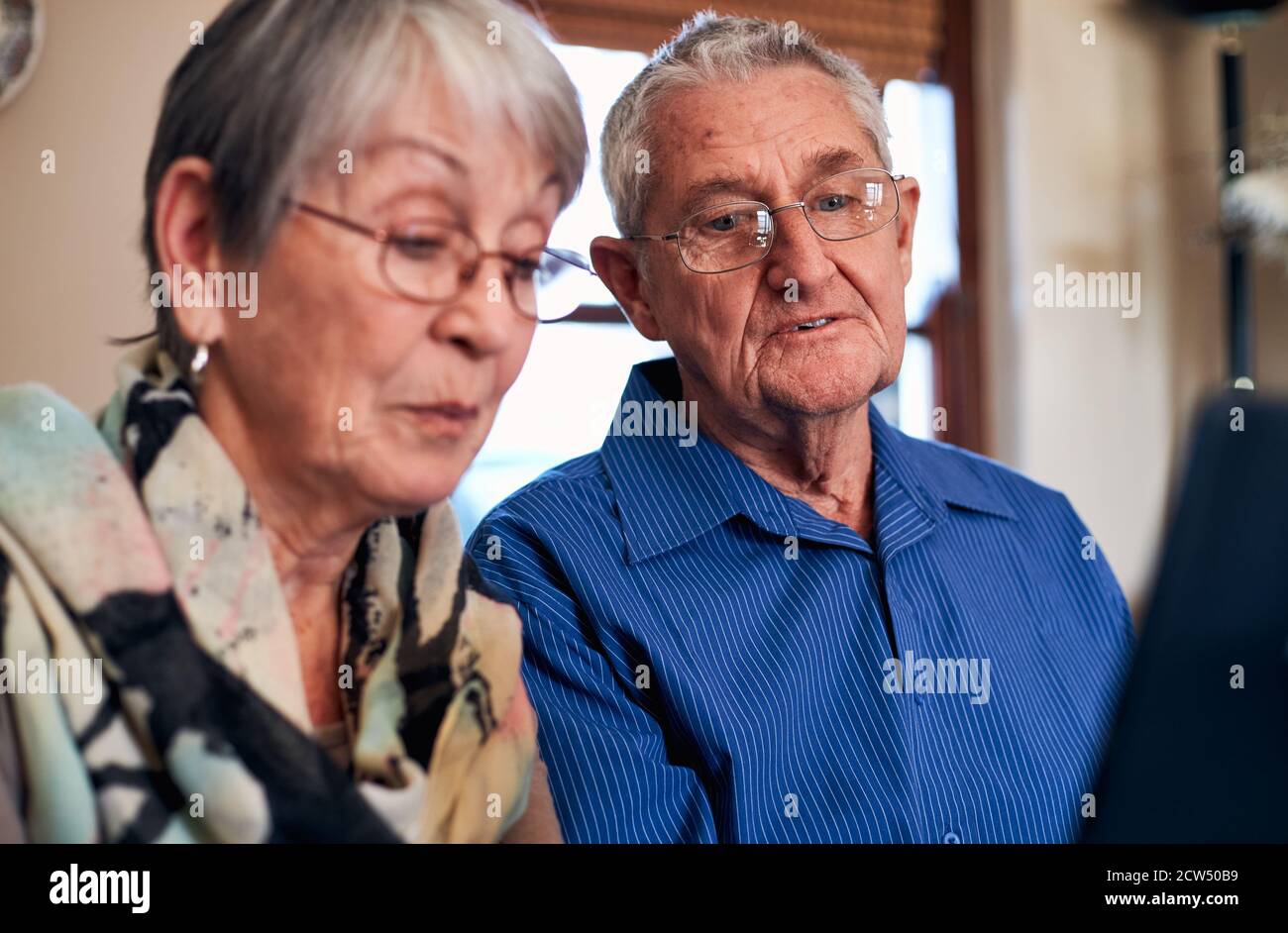 Couple senior à domicile passer un appel vidéo à la famille ou Regarder des films sur une tablette numérique Banque D'Images