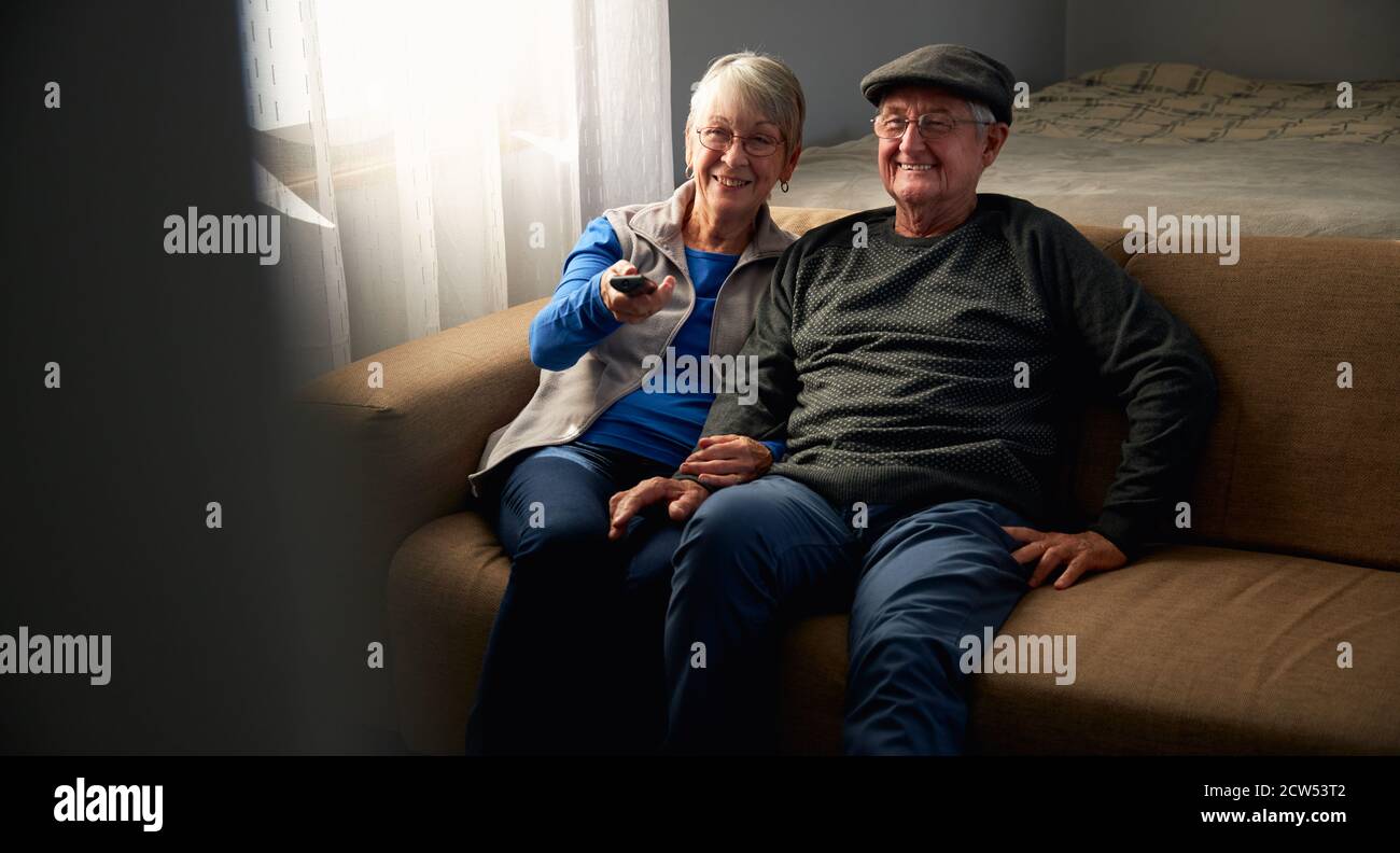 Couple Senior aimant assis sur un canapé à la maison regardant la télévision Ensemble Banque D'Images