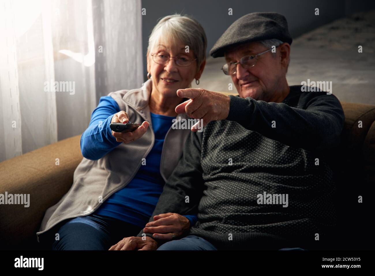 Couple Senior aimant assis sur un canapé à la maison regardant la télévision Ensemble Banque D'Images