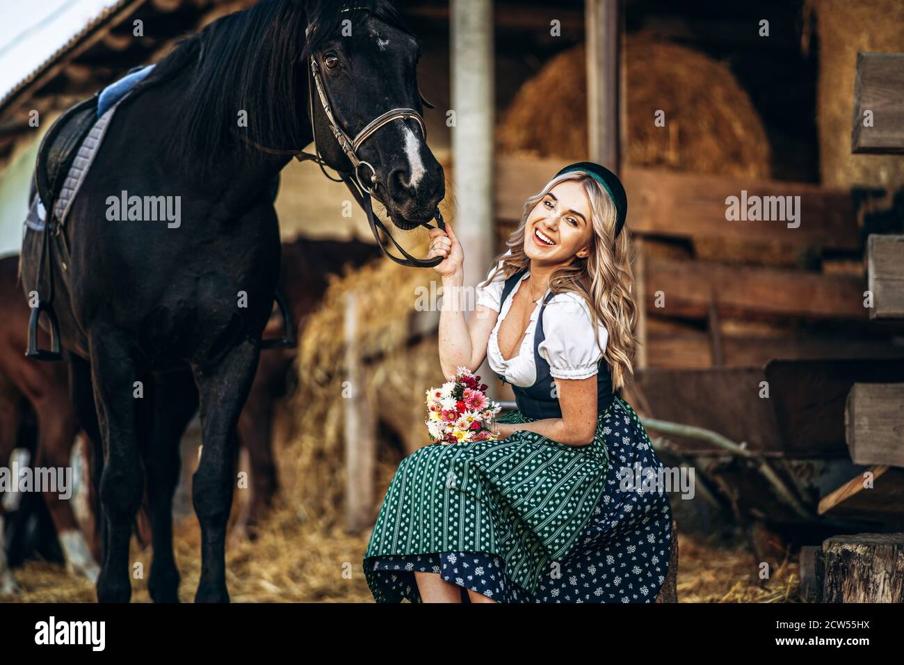 Jolie blonde dans la robe traditionnelle prendre soin de gros cheval noir à  la ferme. Concept de la citoyenneté des animaux et des personnes Photo  Stock - Alamy