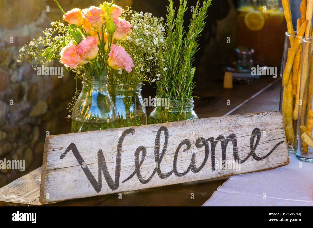 Panneau de bienvenue peint sur bois à côté de fleurs roses Banque D'Images