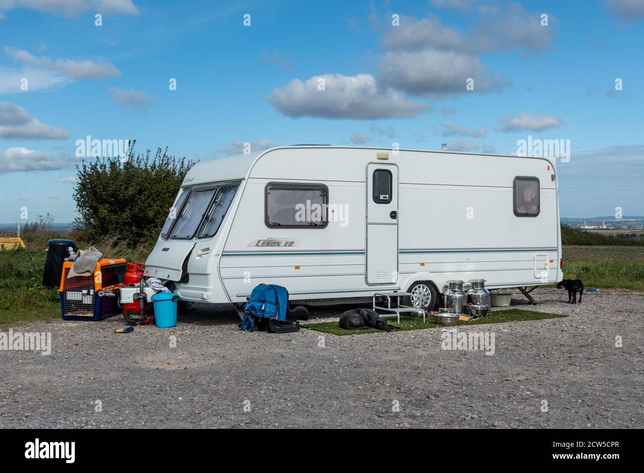 Caravane appartenant à des voyageurs garés illégalement dans un parking de campagne avec chiens et effets personnels à l'extérieur, Royaume-Uni Banque D'Images