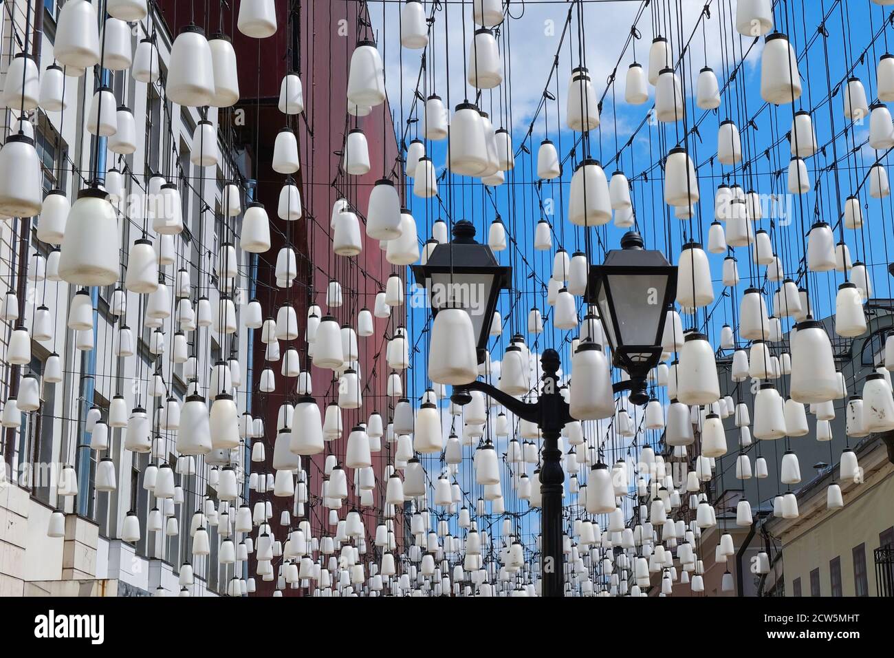 Lanterne de rue classique d'époque avec abat-jour en verre blanc sur fond de composition décorative de lumières de rue contemporaines blanches. Banque D'Images