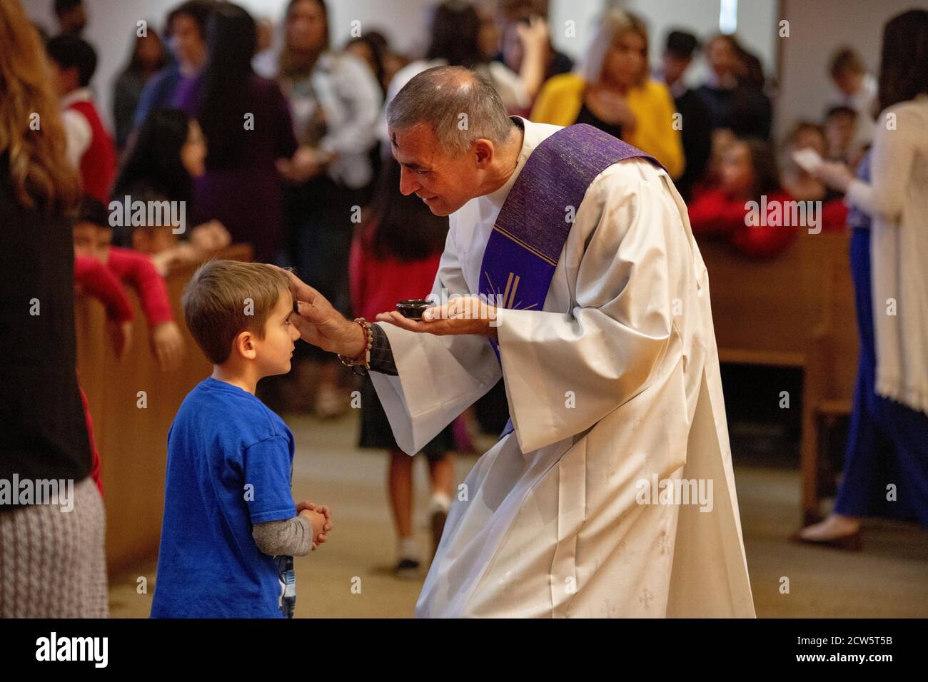 Un diacre rodé fait une croix de cendre sur le front d'un garçon pendant les services du mercredi des cendres dans une église catholique du sud de la Californie. Banque D'Images