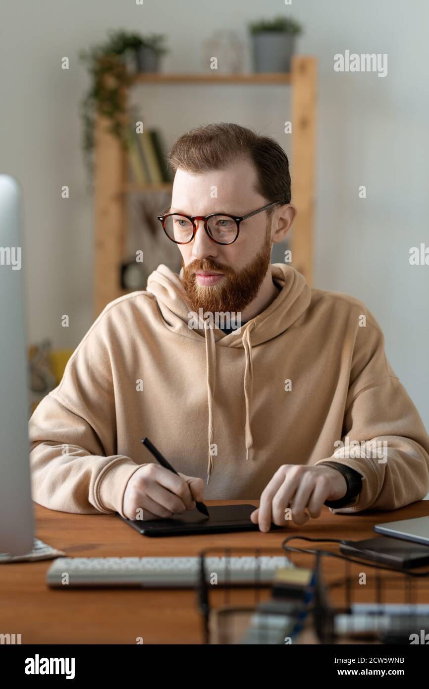 Jeune designer indépendant sérieux contemporain utilisant un pavé tactile et un stylet Banque D'Images