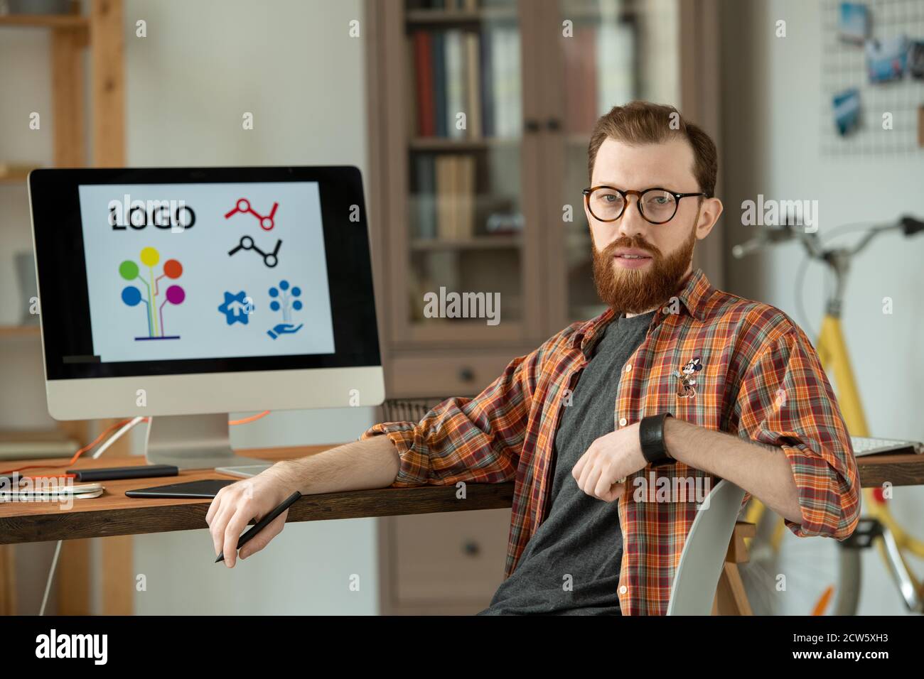 Homme designer réussi assis sur une chaise près d'une table avec ordinateur moniteur Banque D'Images