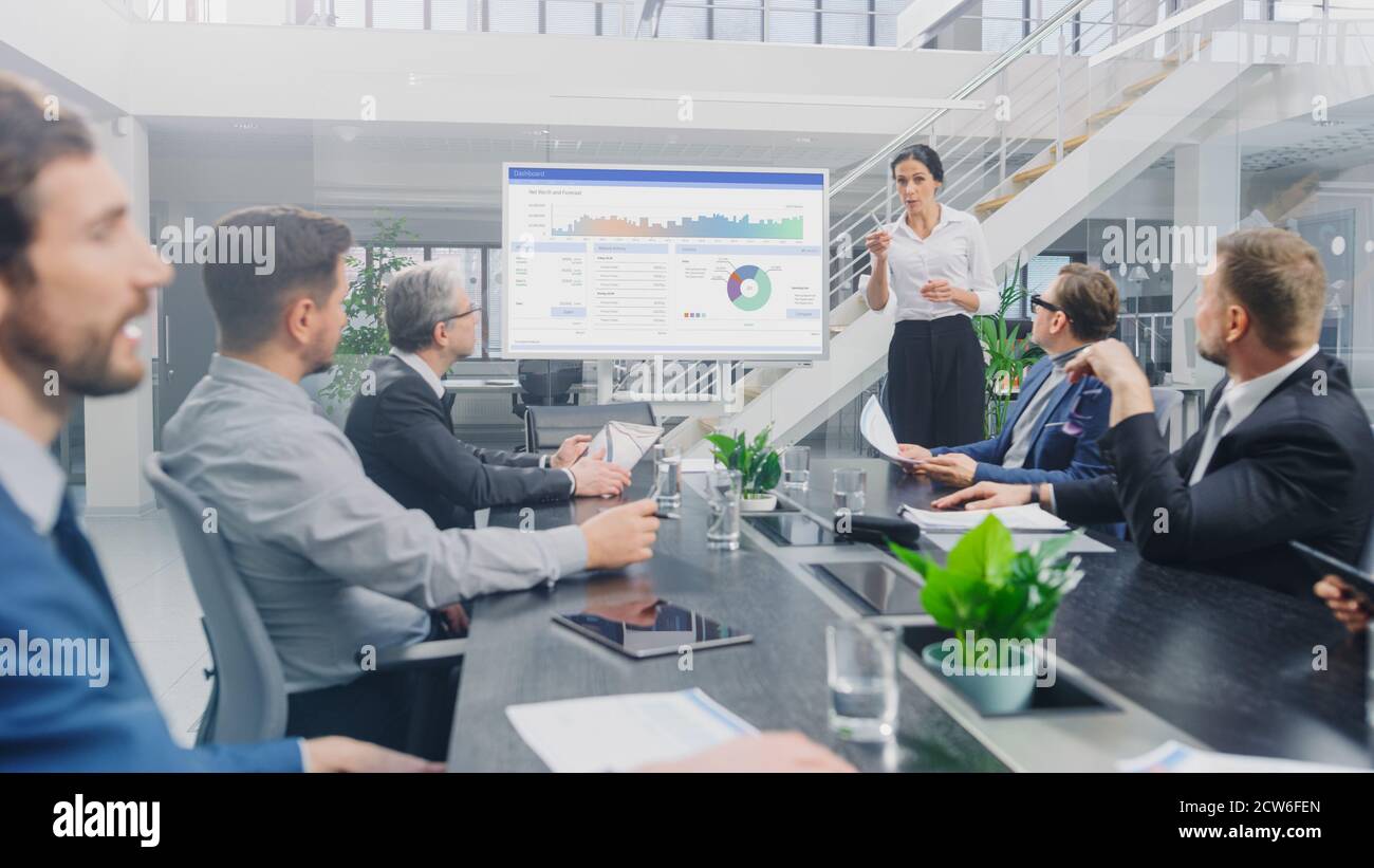 Dans la salle de réunion d'entreprise : l'analyste féminin utilise le tableau blanc interactif numérique pour la présentation à un conseil d'administration, à des avocats et à des investisseurs Banque D'Images