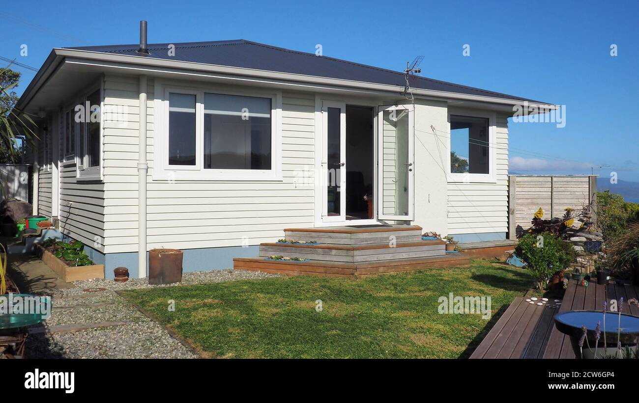 1959 maison en bois (NZ) avec cheminée enlevée au-dessus du toit pour la précaution contre le tremblement de terre. Cheminée restante utilisée comme support de corde à linge. Banque D'Images