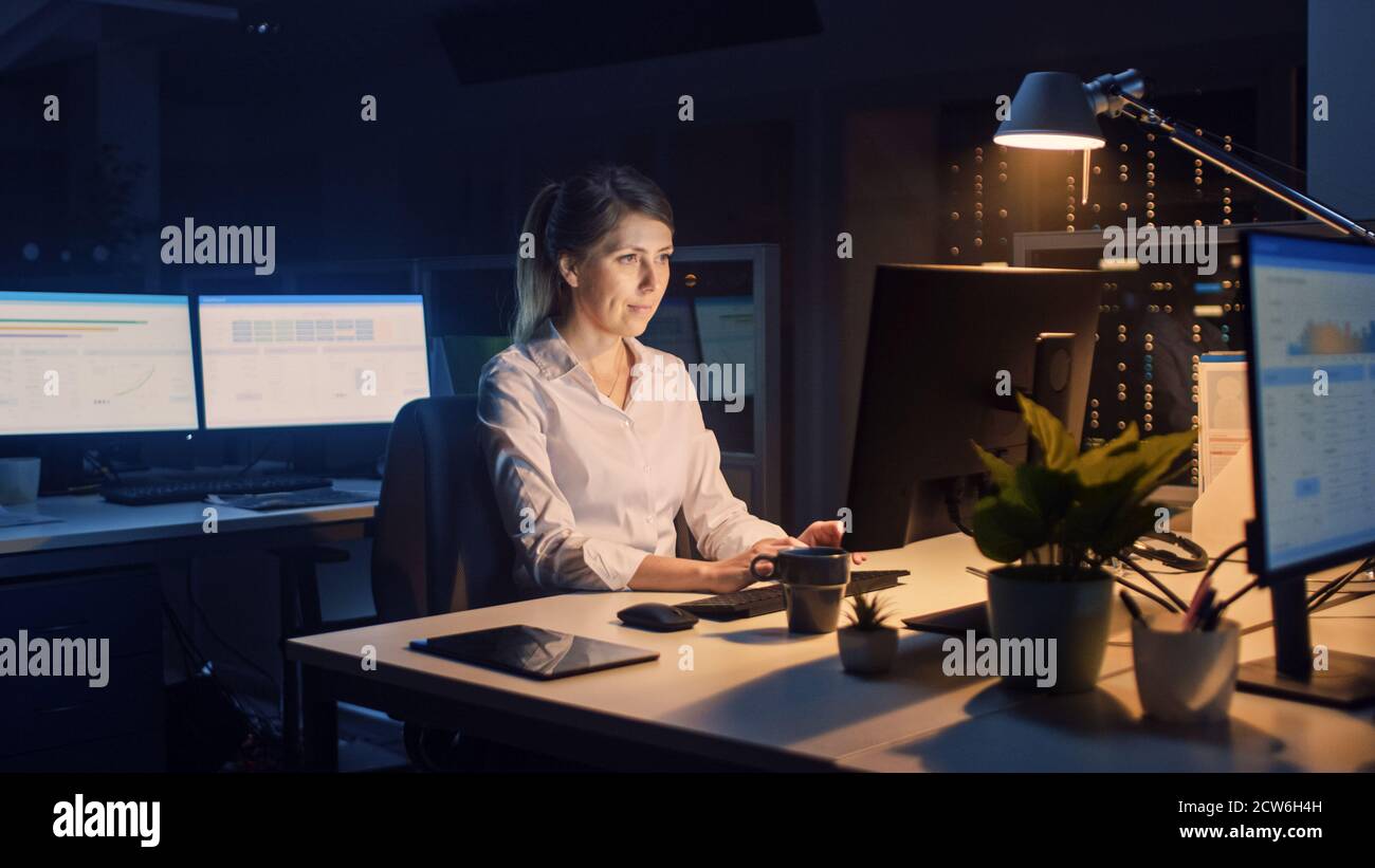 Travailler tard dans la nuit au bureau : femme d'affaires utilisant un ordinateur de bureau, analyser, utiliser des documents, résoudre des problèmes, terminer le projet Banque D'Images
