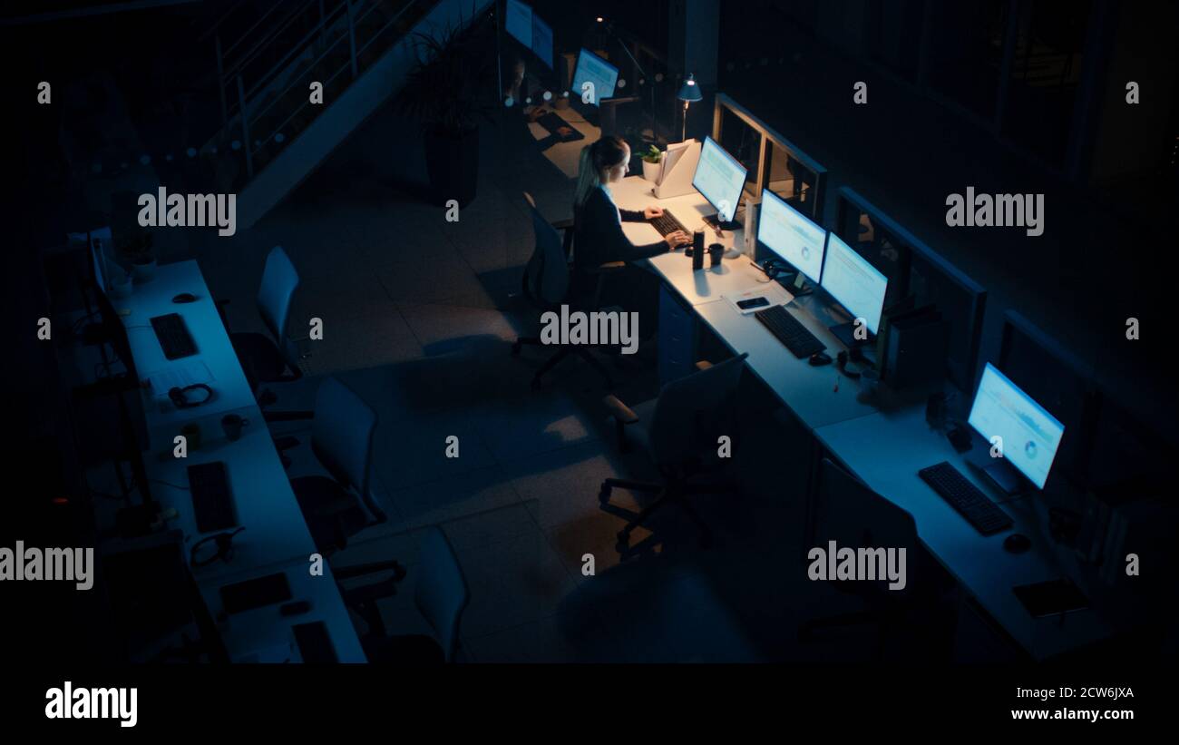 Travailler tard dans la nuit au bureau : femme d'affaires utilisant un ordinateur de bureau, discussion, analyse, utilisation de documents, résolution de problèmes, finition Banque D'Images