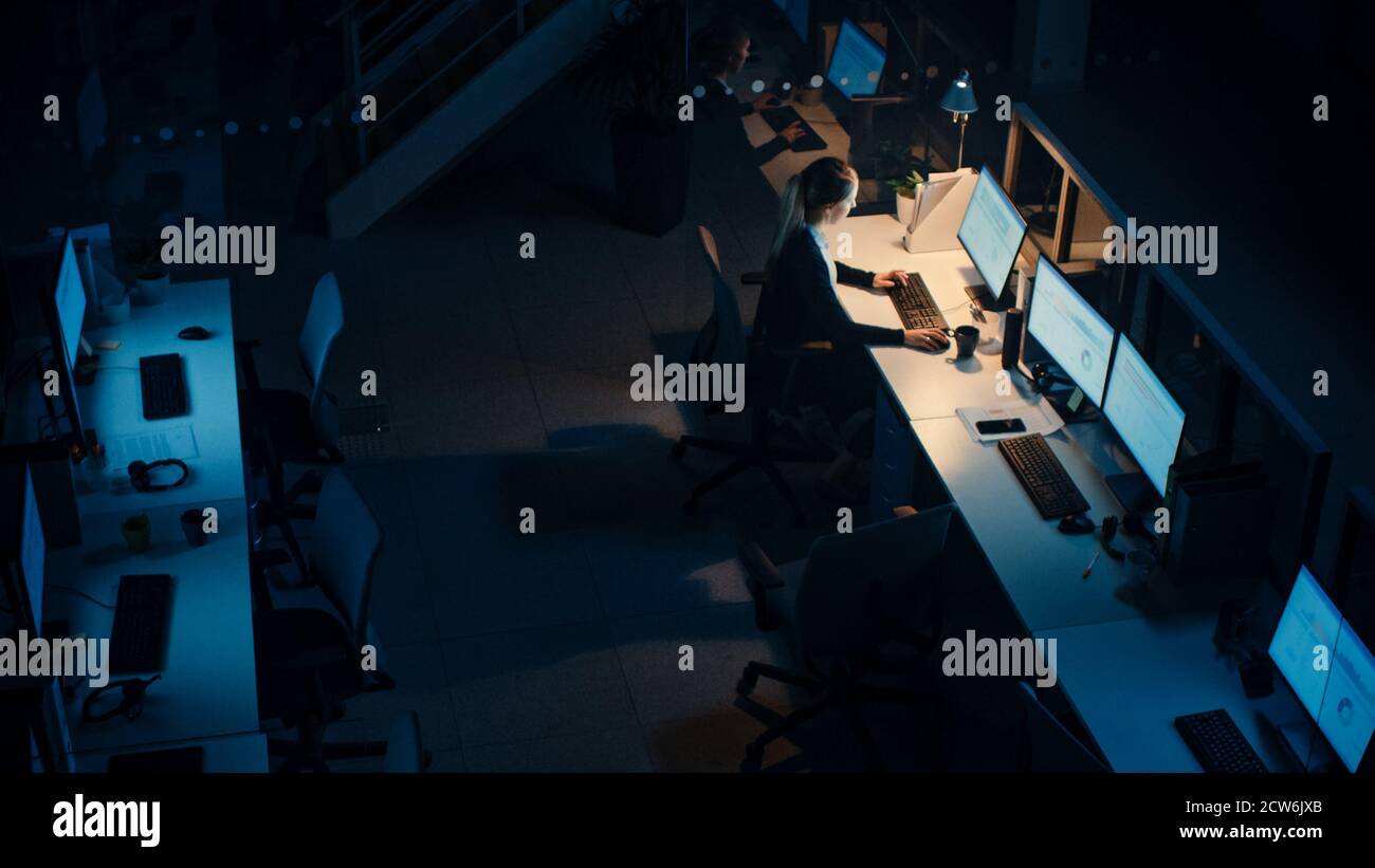 Travailler tard dans la nuit au bureau : femme d'affaires utilisant un ordinateur de bureau, discussion, analyse, utilisation de documents, résolution de problèmes, finition Banque D'Images