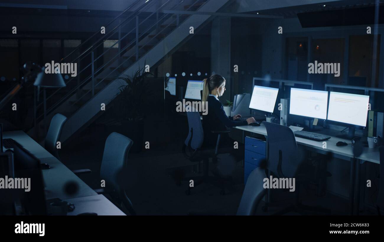 Travailler tard dans la nuit au bureau : femme d'affaires utilisant un ordinateur de bureau, analyser, utiliser des documents, résoudre des problèmes, terminer le projet. Banque D'Images