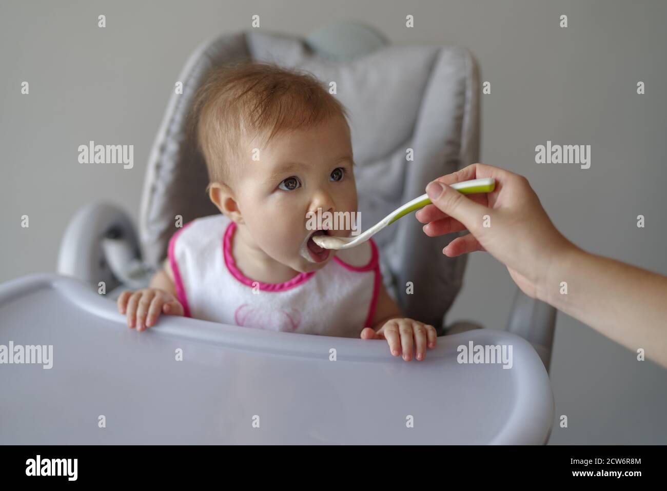 Mère nourrissant bébé fille avec une cuillère dans une chaise haute Banque D'Images