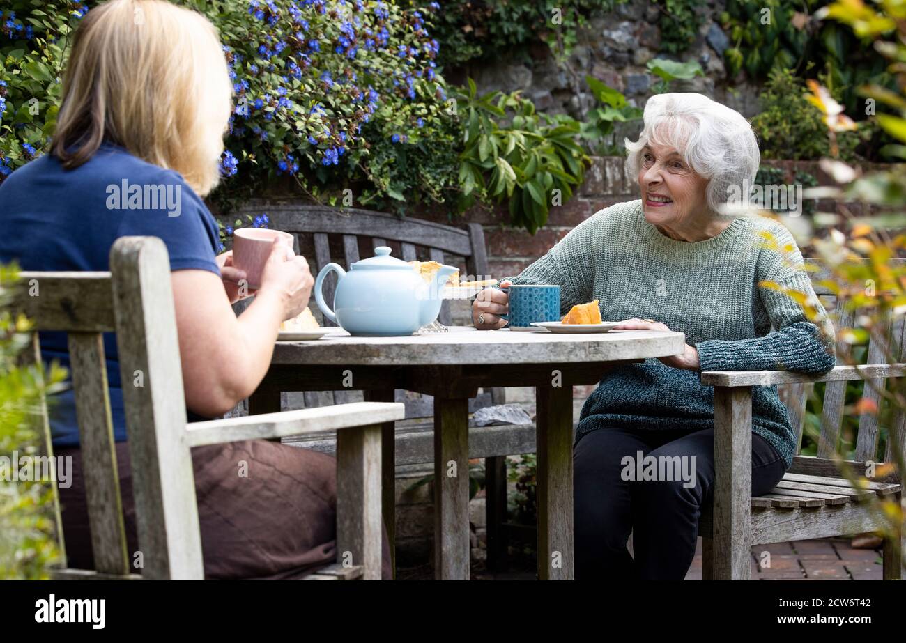 Femme d'âge mûr rendant visite à la mère sénior Lonely dans le jardin pendant le verrouillage Banque D'Images