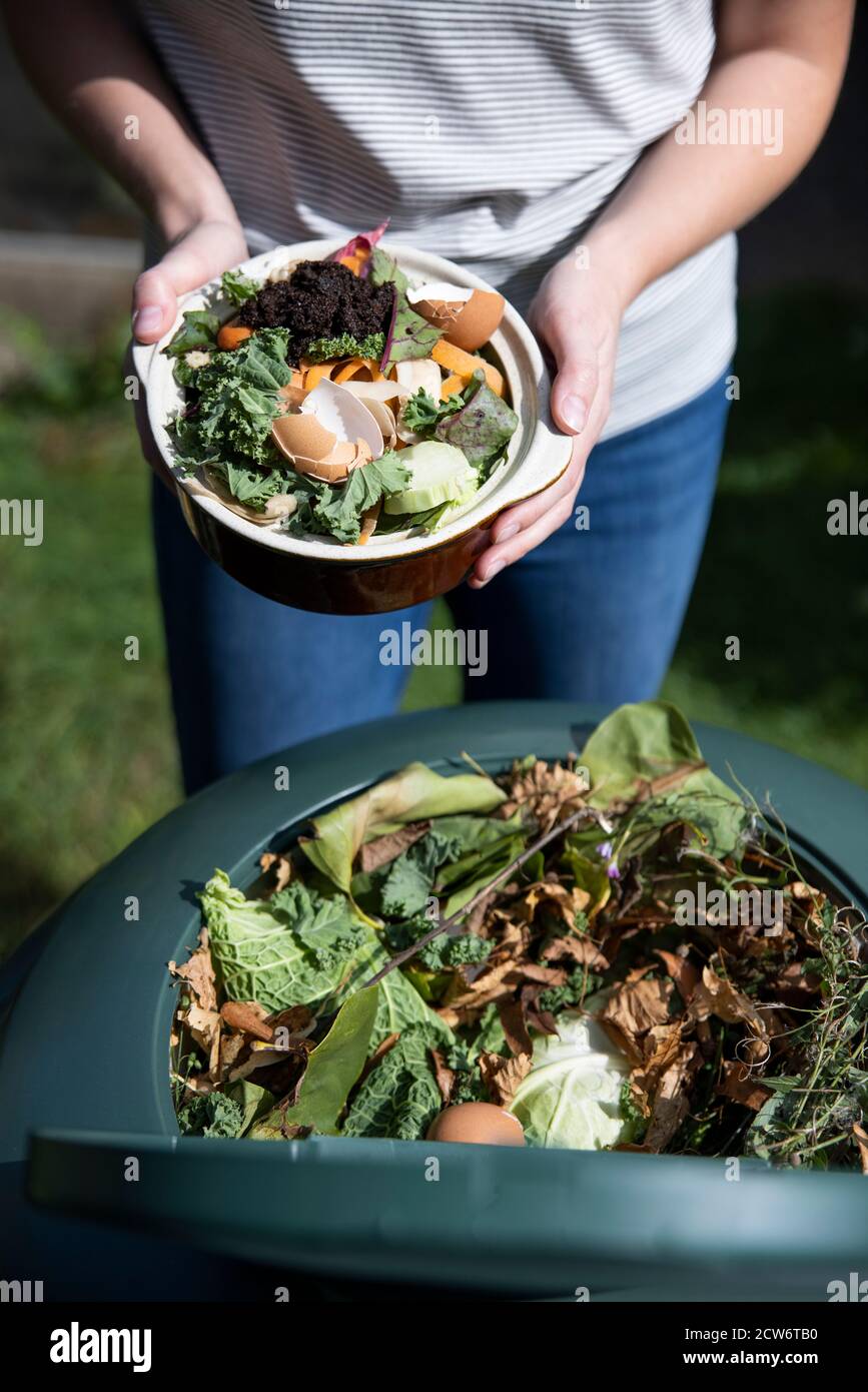 Gros plan de la femme qui vidange les déchets alimentaires dans le composteur de jardin À la maison Banque D'Images