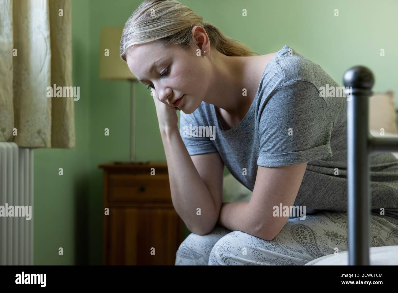 Femme malheureuse souffrant de dépression assis sur un lit portant un pyjama Banque D'Images