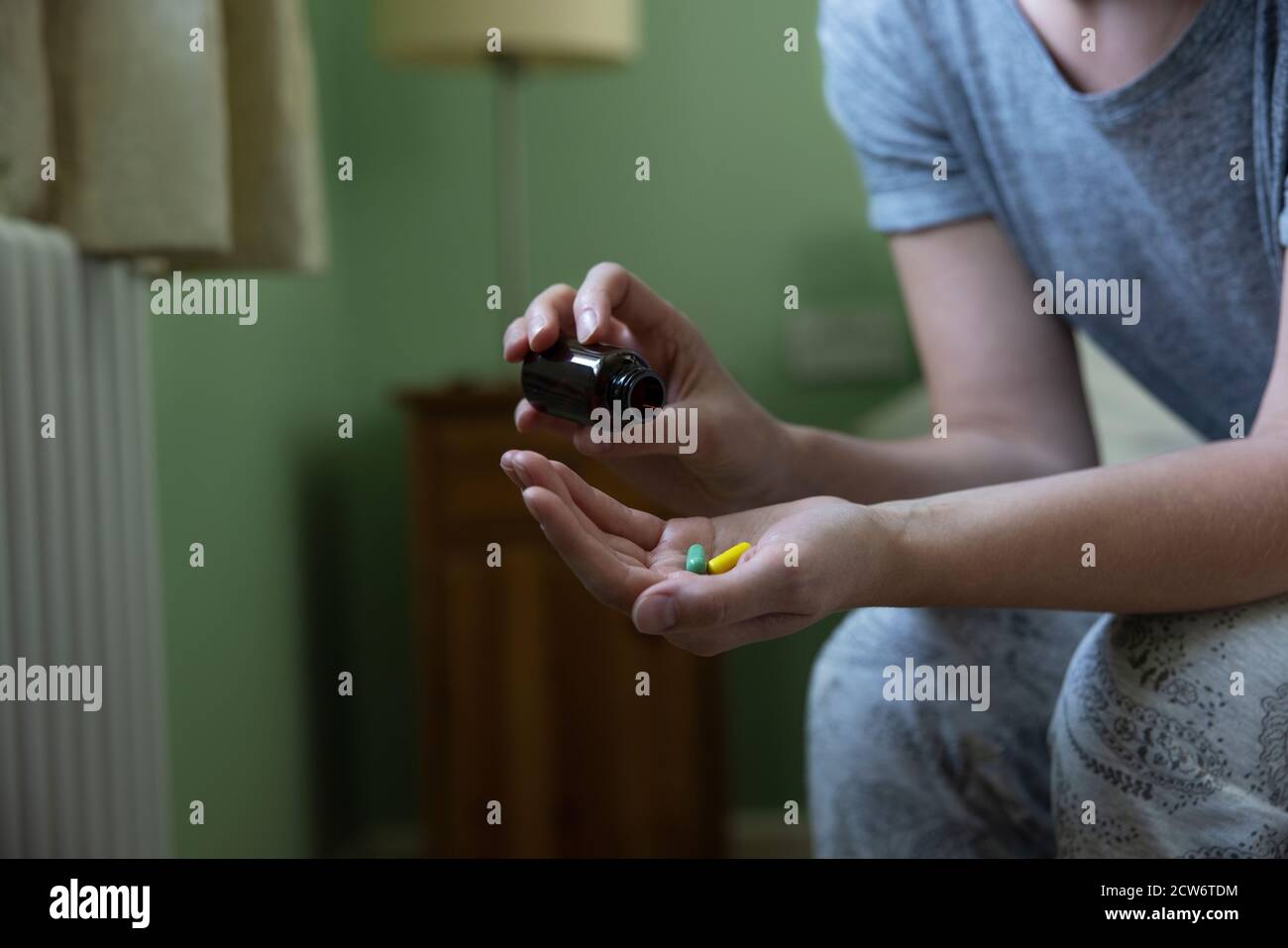 Gros plan d'une femme assise sur un lit portant un pyjama Médicaments Banque D'Images