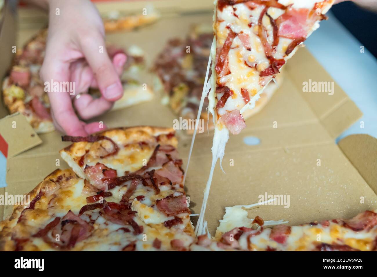 prenez à la main un morceau de pizza avec du fromage fondu. commandez la livraison des aliments. Banque D'Images