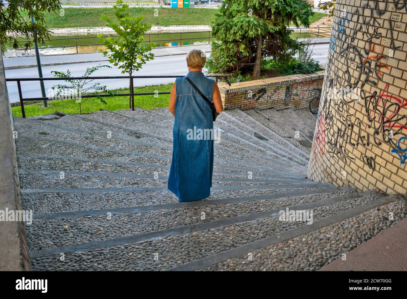Zrenjanin, Serbie, 20 août 2016. Une femme vêtue d'une longue robe en denim qui descend dans les escaliers. Banque D'Images