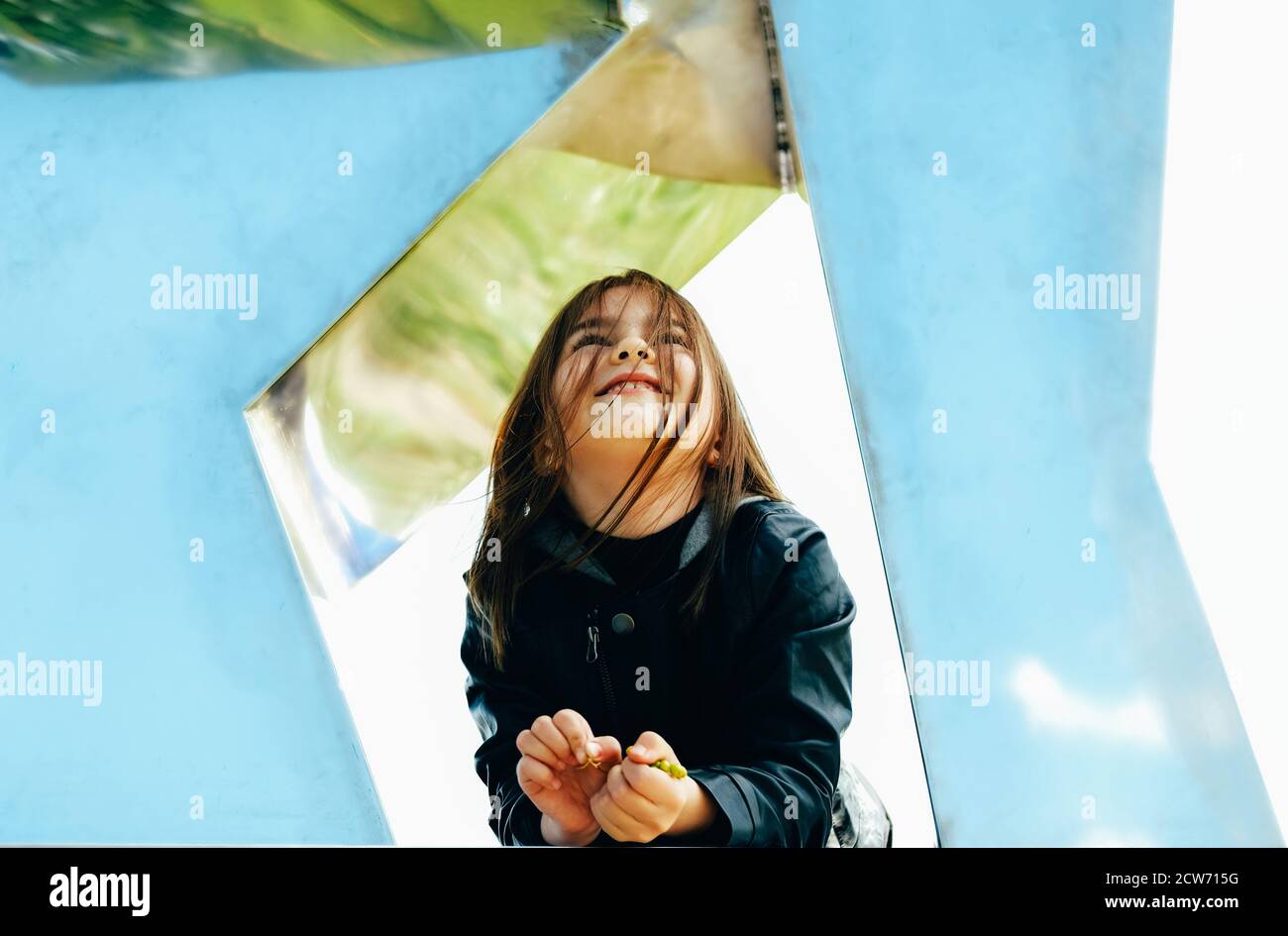 Petite fille dans un élégant ensemble noir d'automne dans un cadre urbain à la recherche du ciel. Banque D'Images