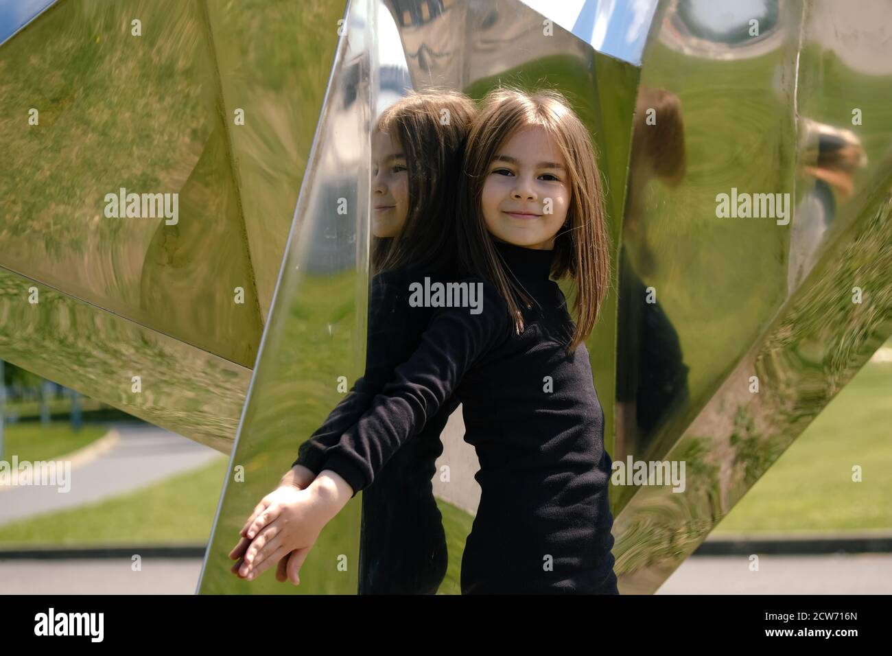 Petite fille dans un élégant ensemble noir d'automne dans un cadre urbain à la recherche du ciel. Banque D'Images