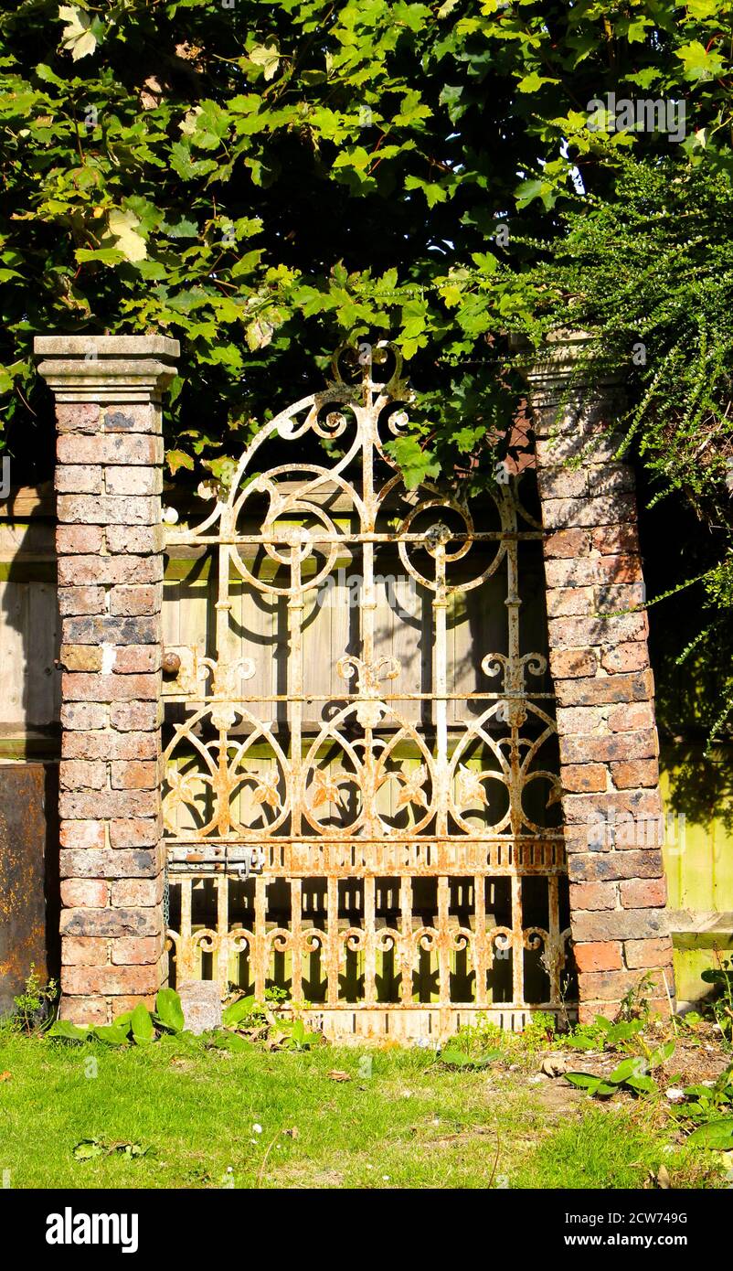 Porte en fer peint rouillé à nulle part à la fin d'un jardin soutenu par des piliers de brique dangereusement penchés South Croydon Surrey Angleterre Royaume-Uni Banque D'Images