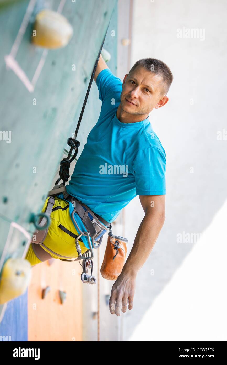 Jeune homme grimpeur reposant sur le mur d'escalade d'entraînement Banque D'Images