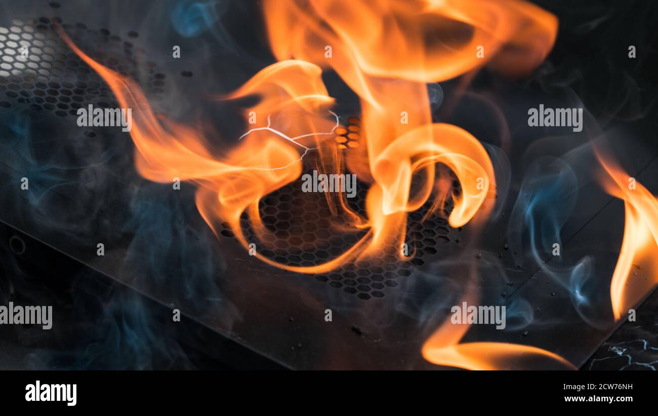 Feu fuyant flamboyant dans une pièce d'épave brûlée sur fond noir. Détail artistique des flammes orange sur la grille de trou de la tôle en feu. Urgence. Banque D'Images